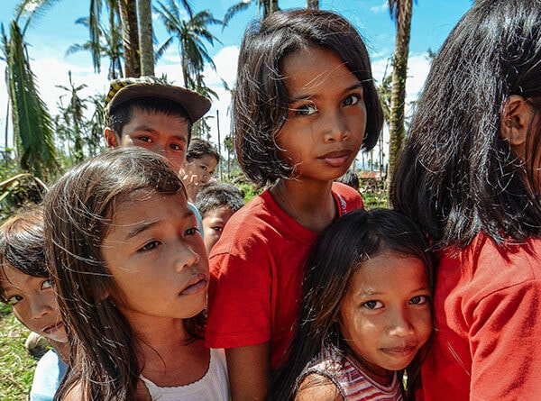 A group of children wearing red shirts standing together on the grass.