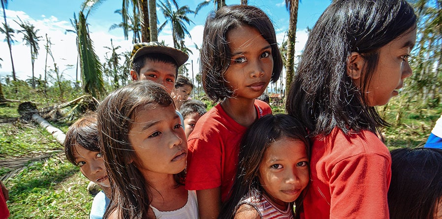 A group of children wearing red shirts standing together on the grass.