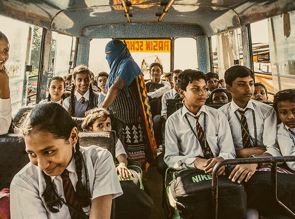 School children on a bus, excitedly chatting and looking out the windows, on their way to school.